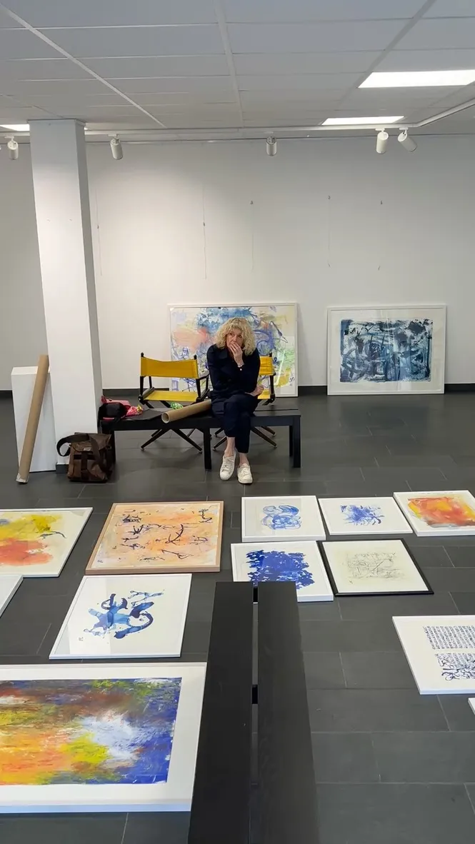 Artist Barbara Möllers surrounded by paintings laid out on the gallery floor during exhibition setup